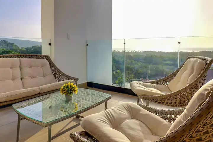 Private terrace lounge with wicker seating and distant sea horizon